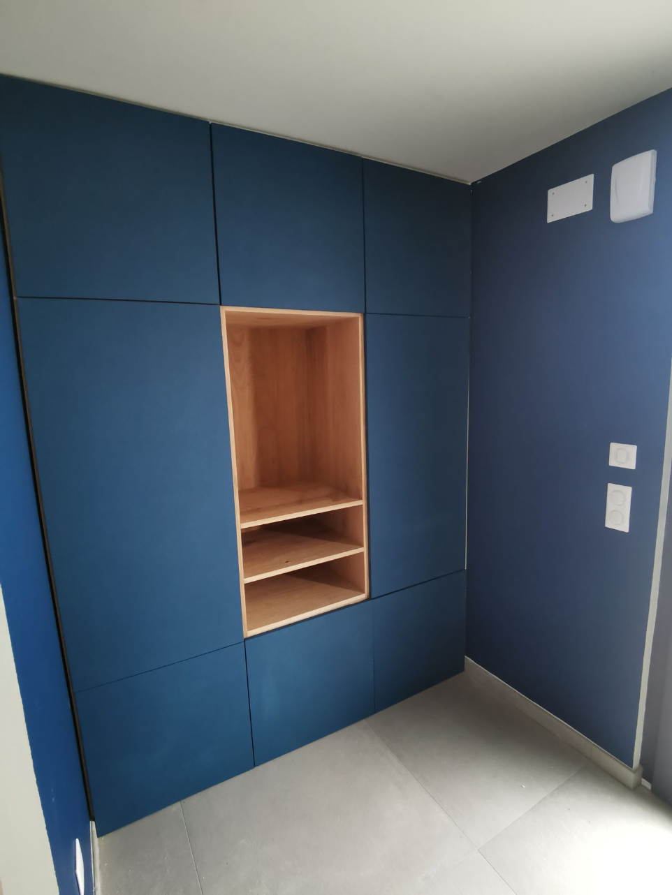 Agencement intérieur sur mesure bleu avec niche en bois, réalisé par SHIZEN DESIGN en Alsace